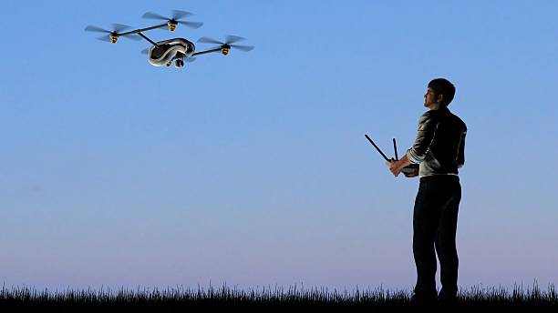 homem operando um quadrocopter drone ao pôr do sol usando um controlador - video three dimensional shape surveillance watching - fotografias e filmes do acervo