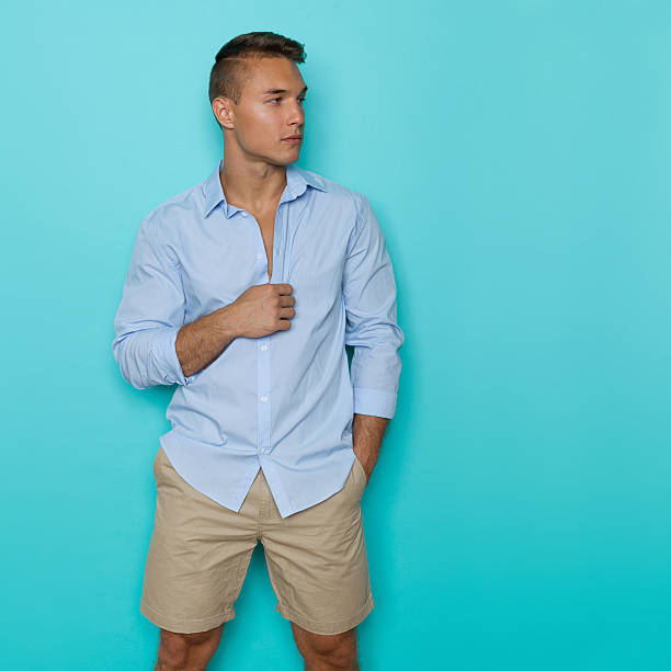 istock Handsome Man In Blue Shirt And Beige Shorts Looking Away 607272156