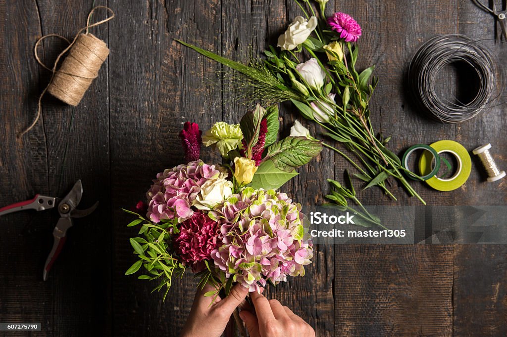 The florist desktop with working tools and ribbons The hands of florist against desktop with working tools and ribbons on wooden background Flower Stock Photo