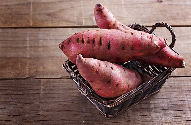 素朴な木製の背景の上にサツマイモ - red potato raw potato red vegetable ストックフォトと画像