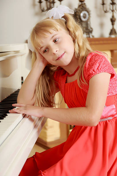 istock Girl sitting at the piano 607278378