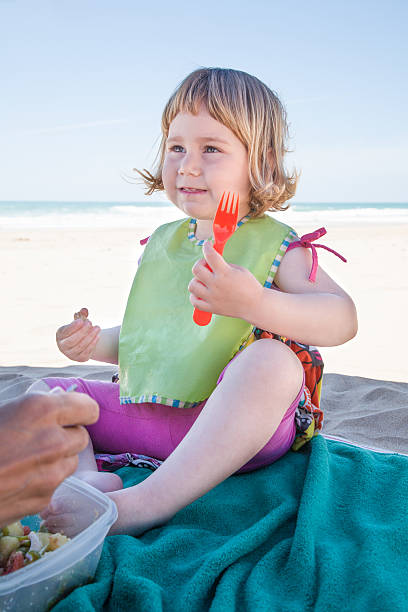 istock little child eating with fork in hand at beach 607280182