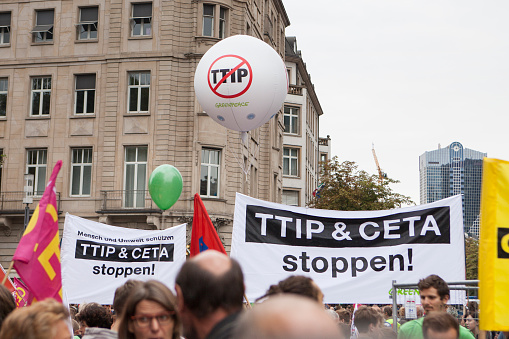 Frankfurt, Germany - September 17, 2016: Protestors holding up banners and flags at large demonstration against TTIP and CETA trade deals in the downtown district of Frankfurt, Germany. More than 30 activist networks organized nationwide demonstrations in seven large cities across Germany under the slogan STOP CETA & TTIP. TTIP (Transatlantic Trade and Investment Partnership) is a projected trade agreement between the EU and the United States of America. CETA (Comprehensive Economic and Trade Agreement) is a projected trade agreement between the EU and Canada.