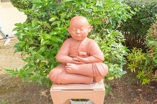 Clay doll of Buddhist novice holding sitting for meditation, Phuket,Thailand