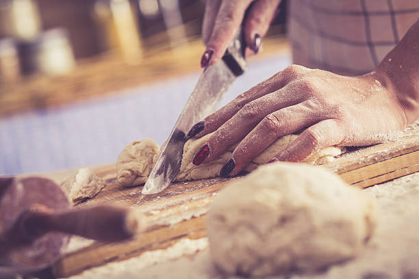istock Close up of female baker cutting dough 607283914