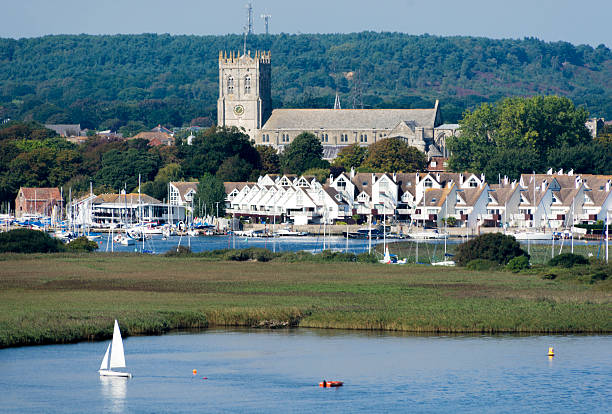Christchurch Priory and Harbour A view of Christchurch harbour with a marin and the large priory church in the background. Boats in the foreground. christchurch england photos stock pictures, royalty-free photos & images
