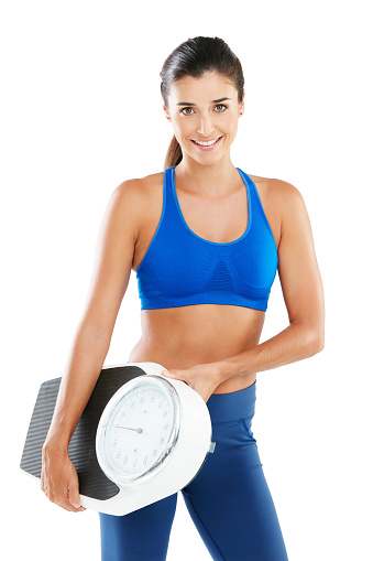 Portrait of a sporty young woman holding a scale against a white background