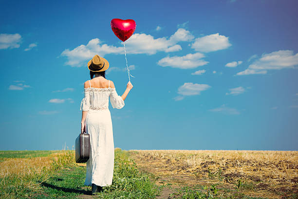 istock young woman with suitcase and balloon 607287160
