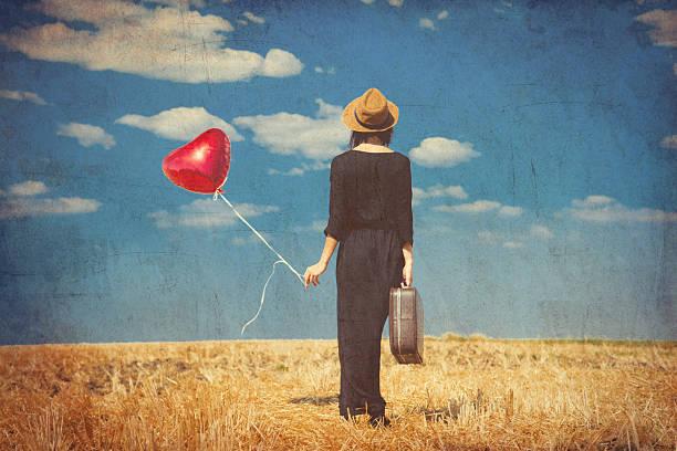 istock young woman with suitcase and balloon 607287950