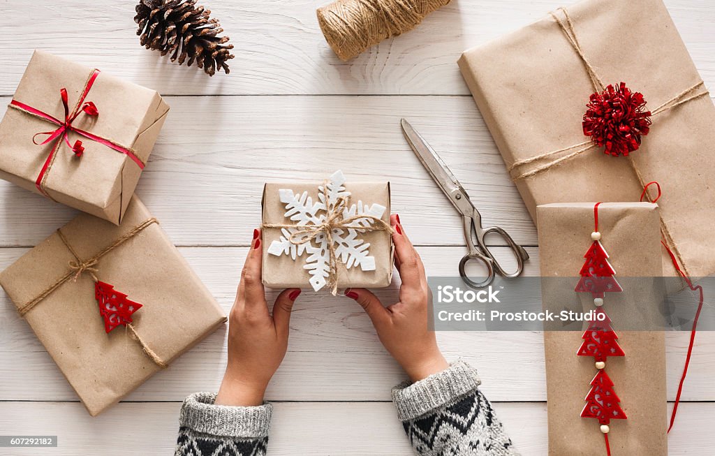 Las manos de la mujer envolviendo el regalo de vacaciones de Navidad con cordel artesanal - Foto de stock de Papel de envolver libre de derechos