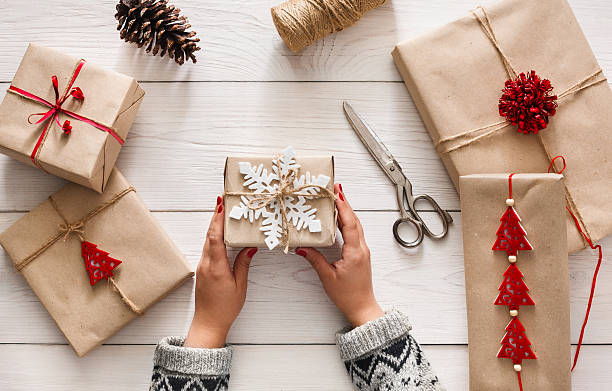 Woman's hands wrapping christmas holiday present with craft twine