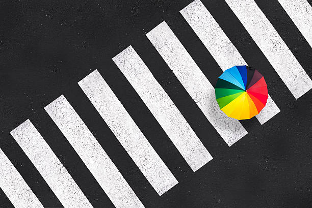 Top view of a rainbow umbrella on a pedestrian crosswalk Top view of a rainbow umbrella on a pedestrian crosswalk crossing sign stock pictures, royalty-free photos & images