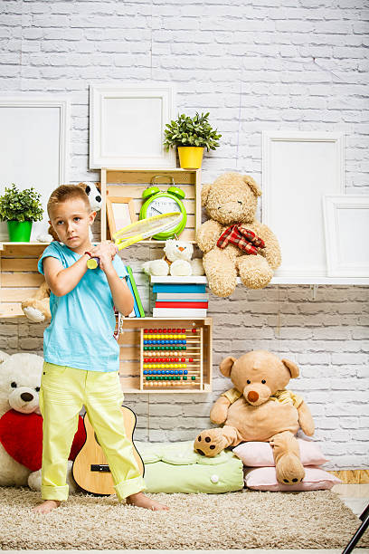 istock Boy playing with tennis racket in his room 607294578