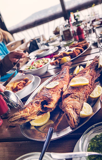 istock Eating Grilled Fish and Fresh Salad in a Restaurant 607295600