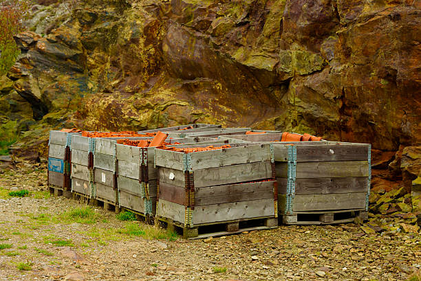 Pallets filled with red roof tiles. Cliffside in background.