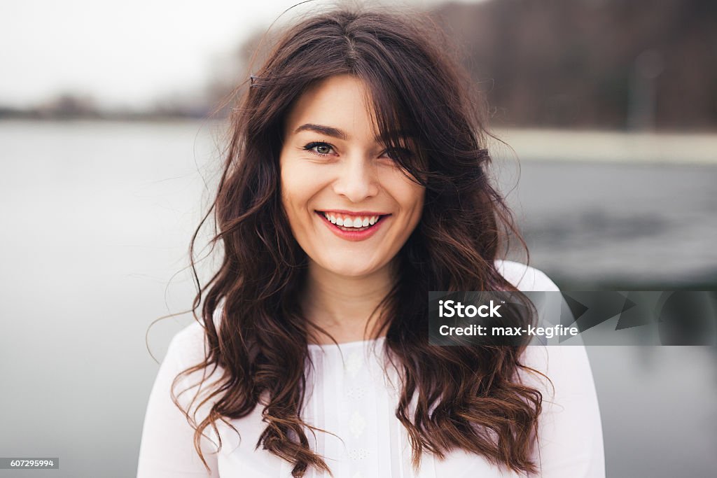 beautiful young girl with a clean fresh face close up close up of a beautiful young girl with a clean fresh face. Woman with brunette curly hair and big eyes smiling Brown Hair Stock Photo