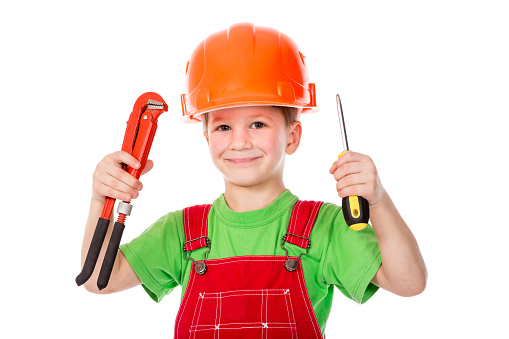 Little builder in red coveralls and helmet with wrench and screwdriver, isolated on white