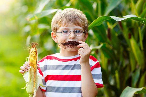 istock Kid boy with sweet corn having fun with moustache 607298148