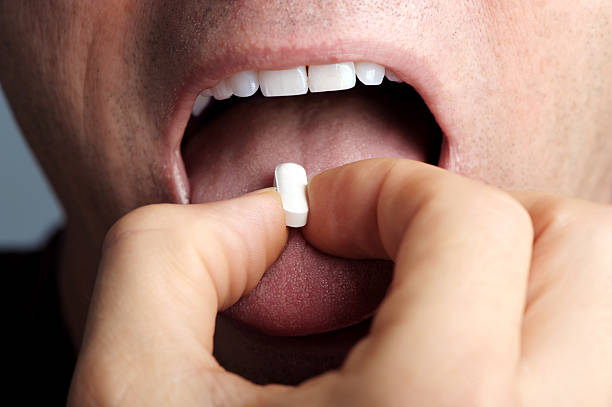 istock Close up man taking pill medicine 607300672