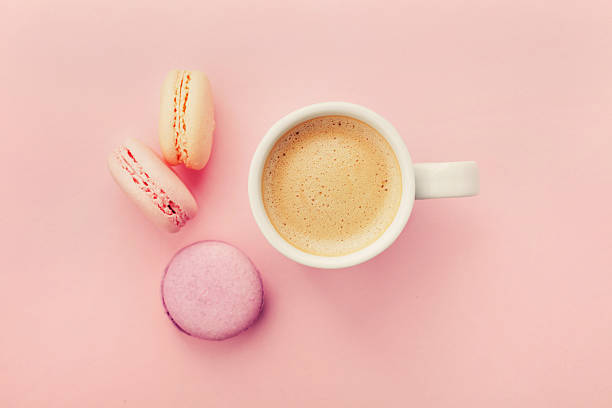 istock Cup of coffee with macaron on pink background from above 607300798