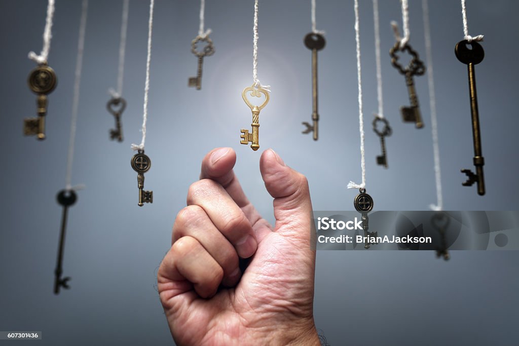 Choosing the key to success Choosing the key to success from hanging keys concept for aspirations, achievement and incentive Key Stock Photo