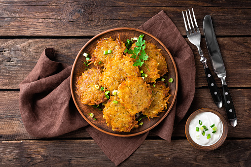 Golden roasted vegetable fritters from potato and red kuri squash in a black pan, also called pumpkin rosti or autumn pancake, copy space, high angle view from above, selected focus