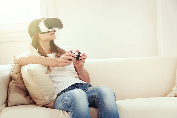 Young woman sitting on couch, using VR glasses