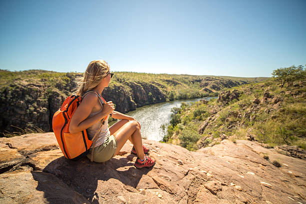 Hiker contemplating spectacular landscape Young woman hiking sits on cliff and looks at view, Katherine Gorges on the background. Beautiful Summer day. northern territory australia stock pictures, royalty-free photos & images
