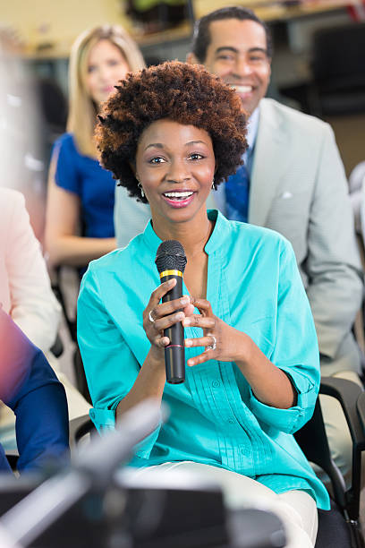 bella donna afroamericana si rivolge a un candidato politico durante l'incontro - african descent question mark holding asking foto e immagini stock