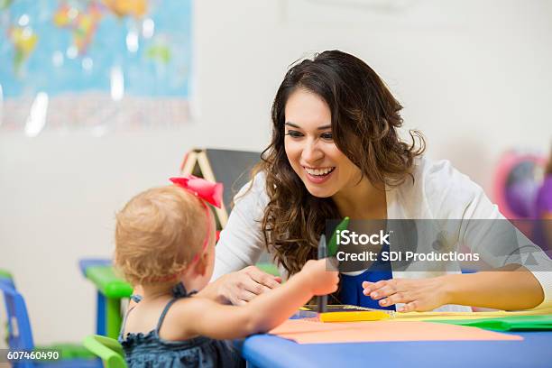 Pretty Daycare Teacher Helps Toddler With Coloring Project Stock Photo - Download Image Now