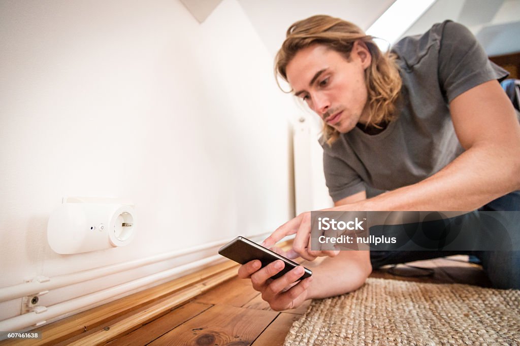Smart Home: Mann programmiert eine Steckdose mit seinem Handy - Lizenzfrei Am Telefon Stock-Foto