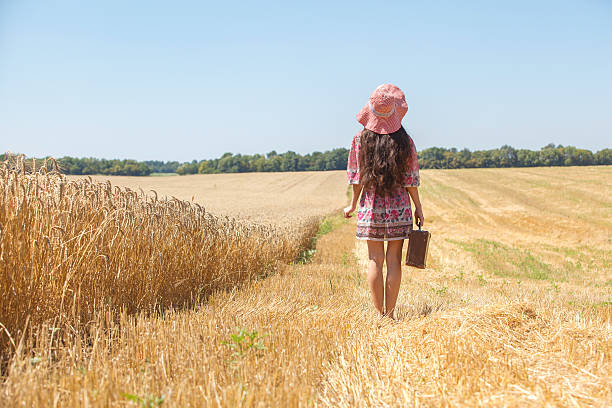 istock girl in hat on wheat field 607461962