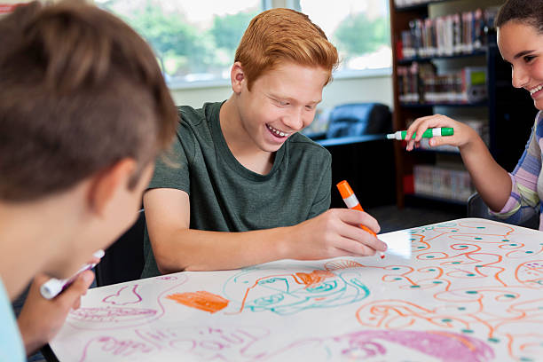 Cheerful teenagers drawing together at local makerspace