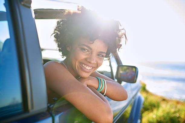 車の窓から身を乗り出す若い女性 ストックフォト