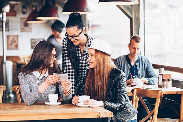istock Smiling young women using smart phone at coffee shop 607465162