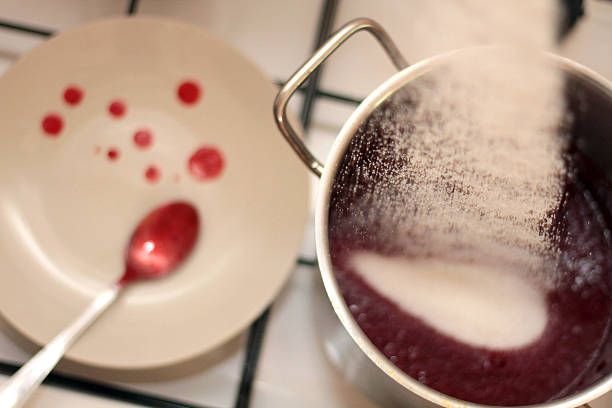 istock Sugar being poured into a pot with boiling mirabelle fruits 607466264