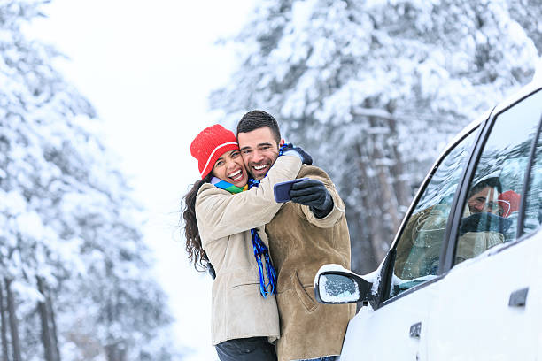 istock Young couple embracing and making selfie on snow footpath 607466282