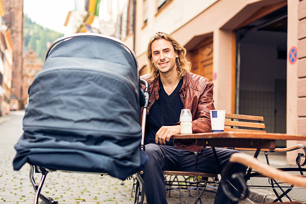 Young father with baby stroller having coffee at a cafe in Heidelberg, Germany.