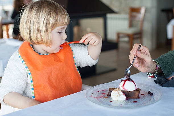 istock little kid eating chocolate cake with woman 607469122