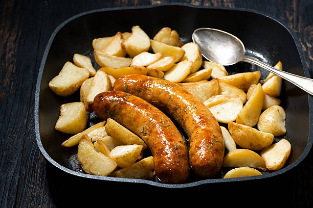 istock fried pork sausages with potatoes in frying pan, horizontal 607469744