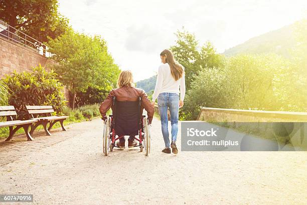 Pareja Joven En Silla De Ruedas Paseando Por El Parque Foto de stock y más banco de imágenes de Silla de ruedas