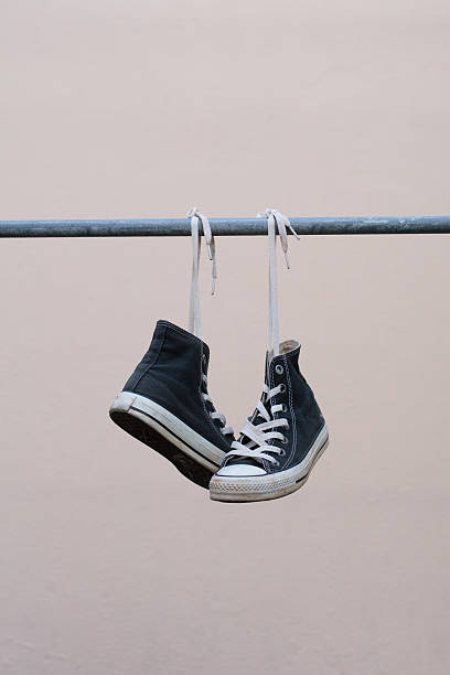 istock Black sneakers hanging on metal bar 607472402