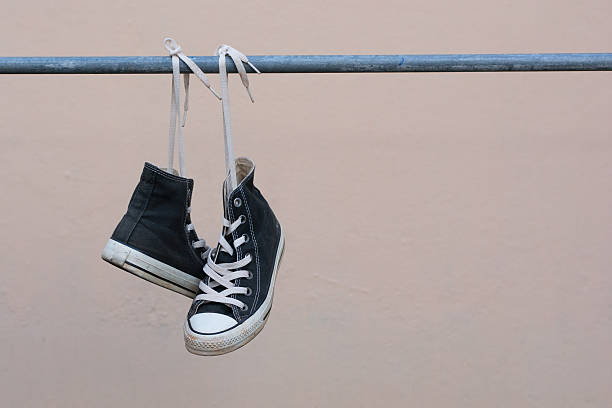 istock Black sneakers hanging on metal bar 607473232
