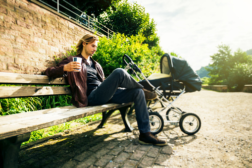 Young father enjoying time outdoors, taking the baby to a park along the banks of the river Neckar in Heidelberg, Germany.
