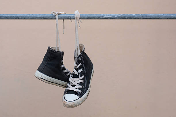 istock Black sneakers hanging on metal bar 607474846
