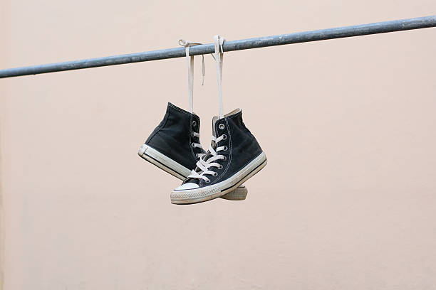 istock Black sneakers hanging on metal bar 607475500