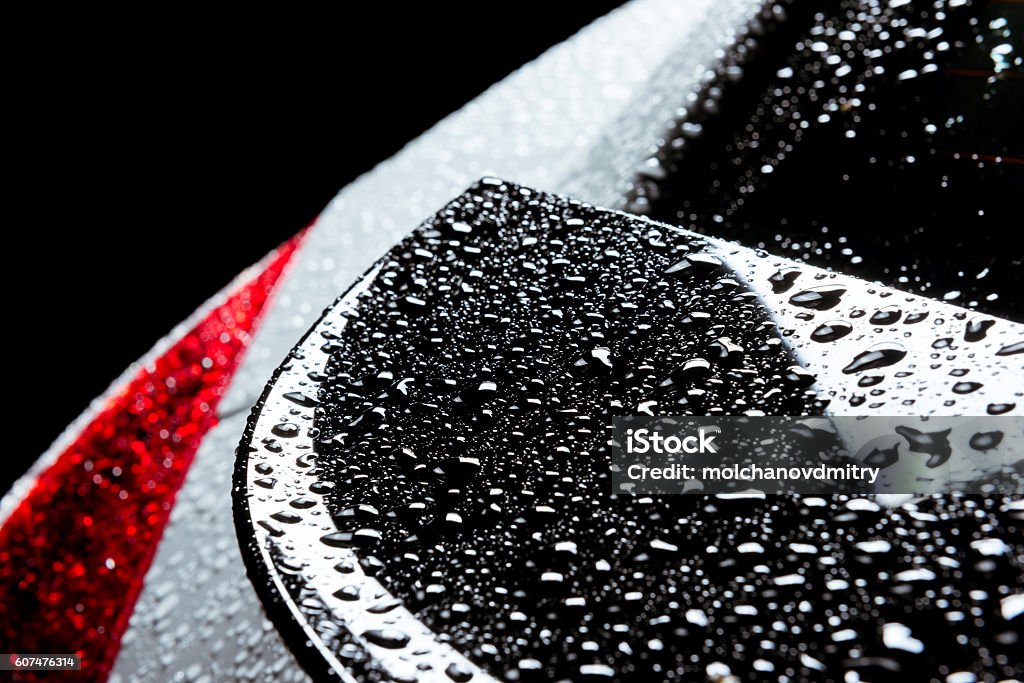 Rain water drops on car body black red Closeup photo of the rain water drops on smooth car body Car Stock Photo