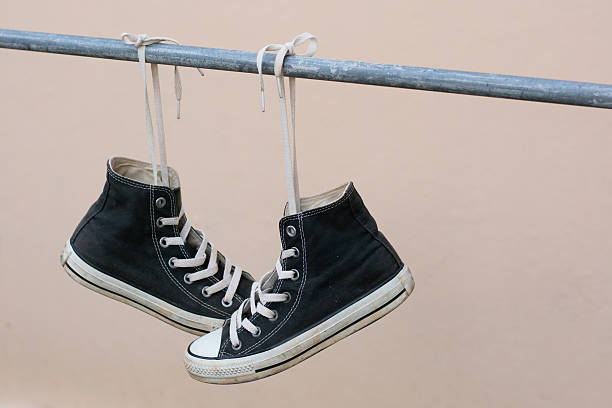 istock Black sneakers hanging on metal bar 607476434