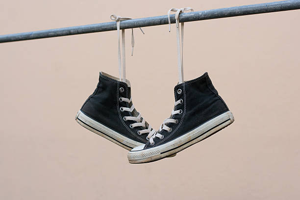 istock Black sneakers hanging on metal bar 607476814