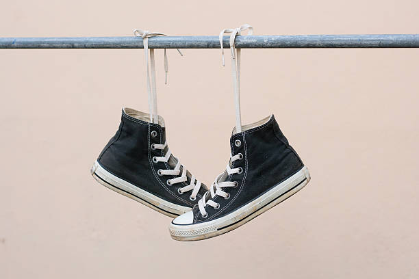 istock Black sneakers hanging on metal bar 607477488